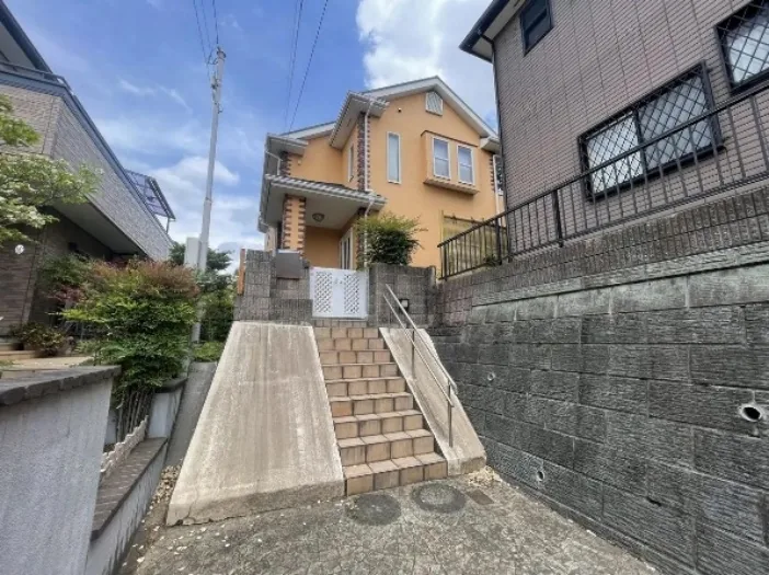 Acceso a una vivienda mediante una escalera junto a una pendiente pronunciada.